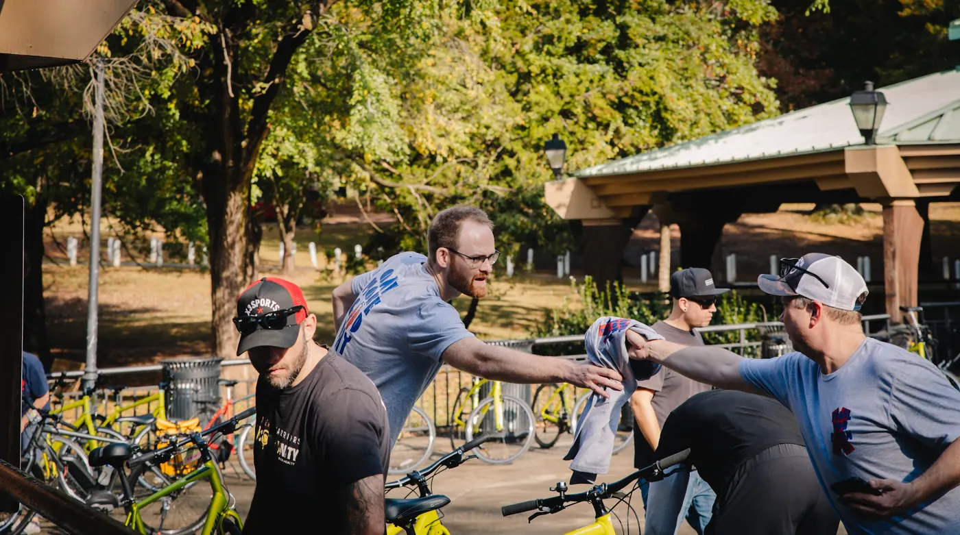 Two participants greet each other beside the bicycles at the 2025 ride.